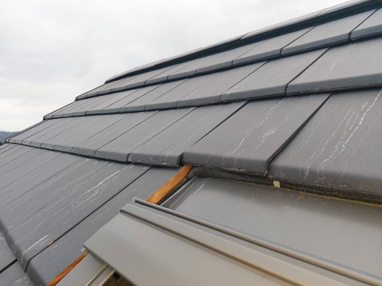 Absence de bande de finition latérale souple autour du Velux et tuile insuffisamment recouvrante, défaut d’étanchéité constaté lors d’une expertise à Seraing.